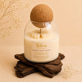 Awaken Your Senses candle by Belora Handcrafts in a glass jar with a cork ball lid, set on a piece of bark