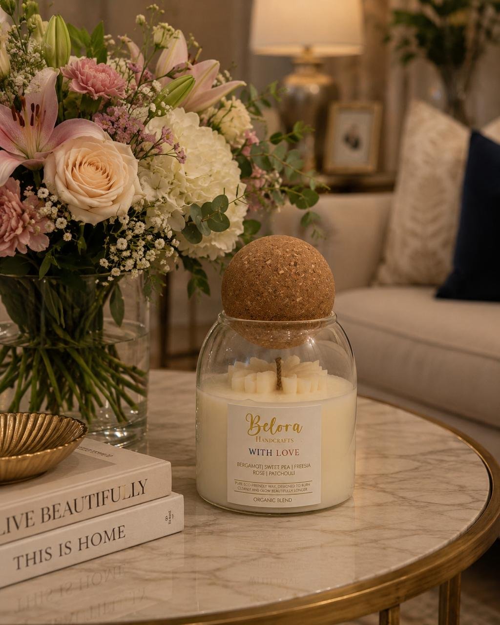 Belora candle on a table beside a bouquet of flowers