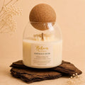 Emerald Dusk candle by Belora Handcrafts in a glass jar with a cork ball lid, set on a piece of bark