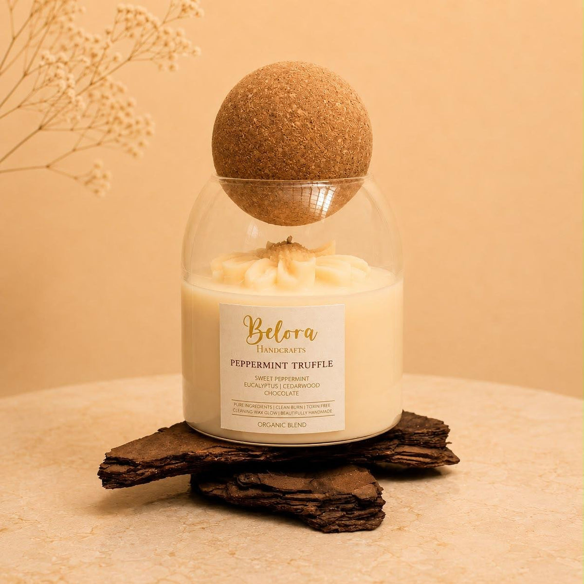 Peppermint Truffle candle by Belora Handcrafts in a glass jar with a cork ball lid, set on a piece of bark