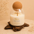 Silent Grove candle by Belora Handcrafts in a glass jar with a cork ball lid, set on a piece of bark